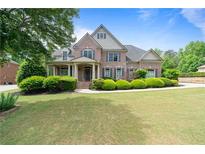Beautiful brick home with manicured lawn, lush shrubbery, and a covered front porch exudes curb appeal at 1758 Rosehedge Nw Way, Kennesaw, GA 30152