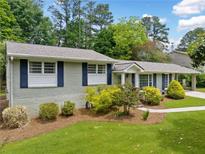 Charming single-story home with light colored brick, blue shutters, mature landscaping, and a welcoming walkway at 3019 Haverford Se Ln, Marietta, GA 30067