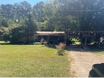 Ranch-style home on a spacious lot with mature trees and an ornamented wooden entrance structure at 1938 Brownsville Rd, Powder Springs, GA 30127