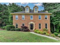 Charming brick home featuring a well-manicured lawn and lush landscaping creating great curb appeal at 1486 Maple Ridge Dr, Suwanee, GA 30024