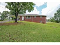 Charming brick home featuring a large front yard, carport, and inviting front entrance at 629 Birchwood Rd, Marietta, GA 30060