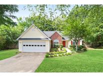 Charming single-story home with a manicured lawn, red door, and a two car garage at 174 Saint Georges Ct, Suwanee, GA 30024