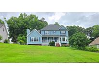 Charming two-story blue home featuring a manicured lawn, inviting porch, and classic architectural details at 4905 Puritan Dr, Sugar Hill, GA 30518