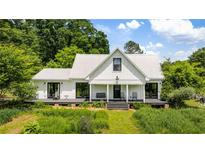 Charming farmhouse with a metal roof and covered porch, nestled among lush greenery at 10975 Hutcheson Ferry Rd, Chattahoochee Hills, GA 30268