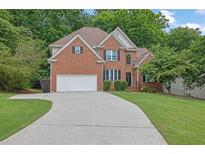 Charming two-story brick home with a manicured lawn, attached garage, and a long driveway at 1558 Ember Oaks Cir, Powder Springs, GA 30127