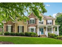Charming two-story home with a stone and siding exterior, a covered porch and beautifully landscaped front yard at 1348 Bridgemill Ave, Canton, GA 30114