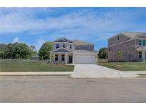 Two-story home with a two-car garage, a well-manicured lawn, and a concrete driveway at 281 Chiswick Loop, Stockbridge, GA 30281