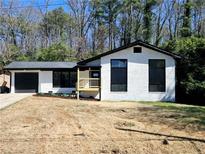 Charming exterior view of a renovated home with white painted brick, black trim, a new porch and garage at 2400 Glenrock Dr, Decatur, GA 30032