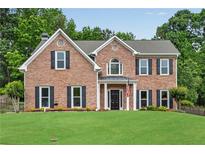 Beautiful brick home with a manicured lawn and symmetrical window design at 260 Roberts Rd, Suwanee, GA 30024