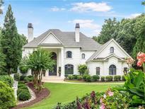Stunning white brick home with lush landscaping, elegant architectural details, and a well-manicured lawn at 8957 Old Southwick Pass, Johns Creek, GA 30022