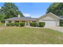 Lovely ranch-style home with a well-maintained front yard, symmetrical landscaping, and an attached garage at 100 Gum Creek Lndg, Oxford, GA 30054