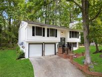 Split-level home featuring a 2-car garage, white siding, and lush greenery at 3512 Lynview W Ct, Decatur, GA 30034