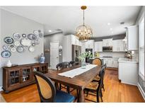 Bright dining room featuring a hardwood floor, farmhouse table with seating for six, and an open view into the adjacent kitchen at 4092 Grand Park Dr, Suwanee, GA 30024
