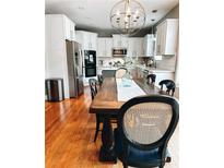 Bright dining room features an expansive wood table, seating for six, and an elegant chandelier above at 4092 Grand Park Dr, Suwanee, GA 30024
