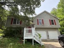 Two-story home with red shutters, white stair railing, and attached two-car garage at 554 Oak Landing Cir, Douglasville, GA 30134