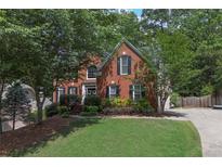Attractive brick home featuring black shutters, a well-manicured lawn, and mature trees at 3004 High Vista Walk, Woodstock, GA 30189