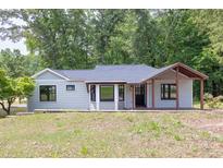 Charming single-story home with a covered front porch, neutral siding, and dark-trimmed windows surrounded by mature trees at 7619 Campground Rd, Cumming, GA 30040