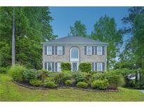 Charming brick home featuring a manicured front lawn, mature trees, and classic architectural details at 2987 Windward Nw Dr, Kennesaw, GA 30152