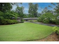 Landscaped front yard with green grass and mature trees leading up to a single story home at 3353 Greenfield Dr, Marietta, GA 30068