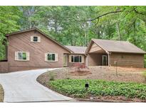Charming home with wood siding, a curved driveway, and lush green landscaping provides great curb appeal at 402 Summit Ridge Ter, Lawrenceville, GA 30046