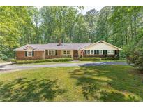 Charming brick ranch with a manicured lawn, mature trees, and a welcoming front porch at 544 W Macedonia Church Rd, Oxford, GA 30054