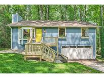 Charming blue home with a bright yellow door and a wooden porch surrounded by lush greenery at 2336 Vistamont Dr, Decatur, GA 30033