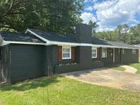 Charming single-story brick home with a well-manicured lawn, dark siding and stylish window shutters at 6914 N Baggett Rd, Douglasville, GA 30134