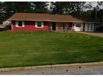 Charming single-story home with a vibrant red brick facade, complemented by a large, well-manicured front yard and mature trees at 1830 Brandy Se Ln, Conyers, GA 30013