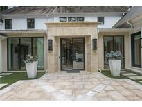 Striking front entrance features a stone patio, modern black framed glass door, and symmetrical planters and sconces at 1 Habersham Nw Way, Atlanta, GA 30305