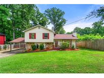 Charming home with a large front yard, carport, red shutters, and stone accents at 273 Hardwood Ln, Lawrenceville, GA 30044
