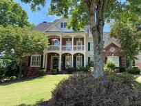 Charming two-story brick home with a welcoming front porch and beautifully landscaped yard at 6009 Castleton Mnr, Cumming, GA 30041