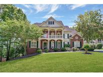Charming two-story brick home featuring a spacious front lawn and a welcoming covered porch with columns at 6009 Castleton Mnr, Cumming, GA 30041