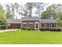 Charming one-story brick home featuring a manicured lawn, colorful flowers, and mature trees at 2118 Allaire Ne Ln, Atlanta, GA 30345