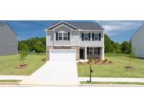 Two-story home featuring a two-car garage, covered entry, and nicely manicured lawn at 215 Amberjack Trail, Covington, GA 30016