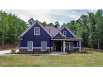 Charming blue house with a well-manicured lawn and inviting front porch surrounded by lush, mature trees at 1056 Riverstone Dr, Social Circle, GA 30025
