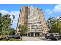 Modern high-rise building featuring a mix of brick and white concrete, mature trees, and ample parking at 215 Piedmont Ne Ave # 507, Atlanta, GA 30308