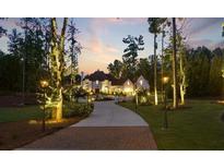 Beautiful sunset view of this home with brick driveway, professionally manicured landscaping, and charming exterior lighting at , Buford, GA 30518