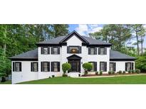 Elegant two-story white brick home with black trim, shutters, and lush landscaping at 1887 Chedworth Ct, Stone Mountain, GA 30087