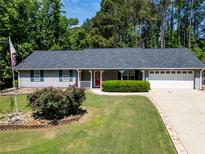 Charming single-story home boasts a well-manicured lawn and a classic red front door at 35 Brooke Holw, Covington, GA 30016