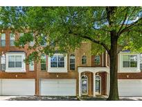 Charming townhome featuring a brick facade, arched windows, a two-car garage, and a covered entryway at 576 Fraser Se St, Atlanta, GA 30312