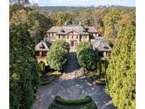 A stately stone mansion with manicured grounds sits amid lush greenery and trees in this aerial view at 3450 Ridgewood Nw Rd, Atlanta, GA 30327