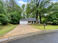 Charming single-Gathering home with a two-car garage and a well-maintained front yard surrounded by mature trees at 6026 Woodcreek Dr, Woodstock, GA 30188