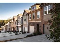 Charming row of townhomes featuring varied facades and attached garages on a tree-lined street at 2692 Avanti Way, Decatur, GA 30035