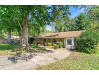 Charming single-story home featuring a brick facade, arched doorways, and mature trees at 2830 Knollview Dr, Decatur, GA 30034