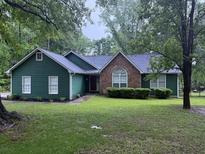 Charming one-story home featuring a brick accent, dark green siding, and a lush front lawn at 608 Fairhaven Blvd, Stockbridge, GA 30281