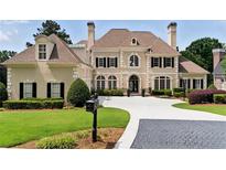 Elegant home with manicured lawn, circular driveway, and classic architectural details at 1409 Spyglass Hill Dr, Johns Creek, GA 30097