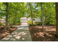 Charming home with stone accents, lush trees, and a long driveway at 110 Fairway Ridge Dr, Johns Creek, GA 30022