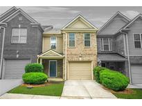 Inviting two-story brick townhome features a one-car garage, lush landscaping, and a welcoming front entrance at 1622 Honeysuckle Path, Conyers, GA 30012