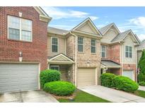 Attractive brick townhome with an attached garage, and well-manicured landscaping and a blue sky backdrop at 1622 Honeysuckle Path, Conyers, GA 30012