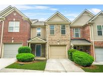 Charming townhome featuring a two-car garage, well-maintained lawn, and inviting entryway at 1622 Honeysuckle Path, Conyers, GA 30012
